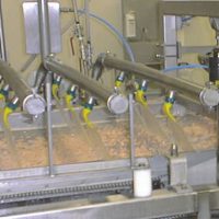 A cereal manufacturer needed to separate and spread the individual pieces of product before they were coated. The shaking zone is isolated, by springs, from the mainframe. An NTK<SUP>®</SUP> Oscillator is fastened to the shaking zone frame, vibrating the conveyor belt and cereal.