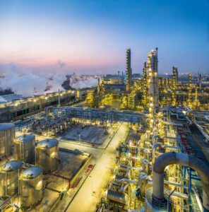 Aerial view captures a large chemical plant illuminated at twilight, showcasing the scale and complexity of industrial operations as night falls.