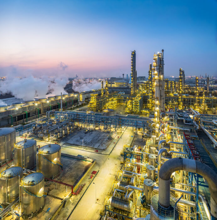 Aerial view captures a large chemical plant illuminated at twilight, showcasing the scale and complexity of industrial operations as night falls.